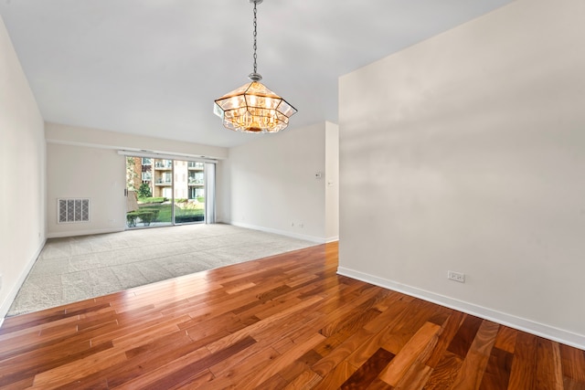 unfurnished room featuring a notable chandelier and hardwood / wood-style floors