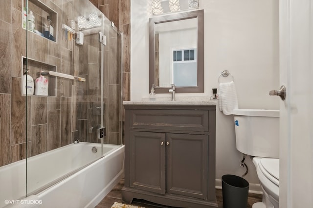 full bathroom featuring toilet, enclosed tub / shower combo, and vanity