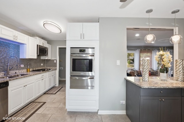 kitchen featuring stainless steel appliances, sink, pendant lighting, white cabinetry, and light stone counters