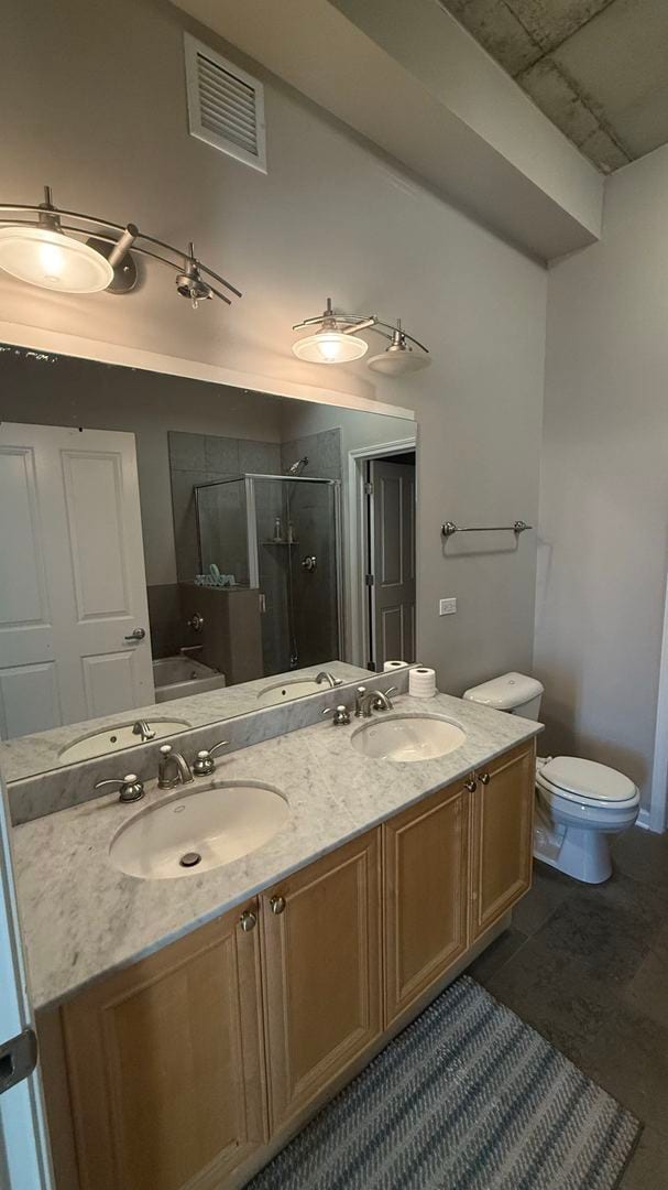 bathroom featuring a shower with door, toilet, vanity, and tile patterned floors