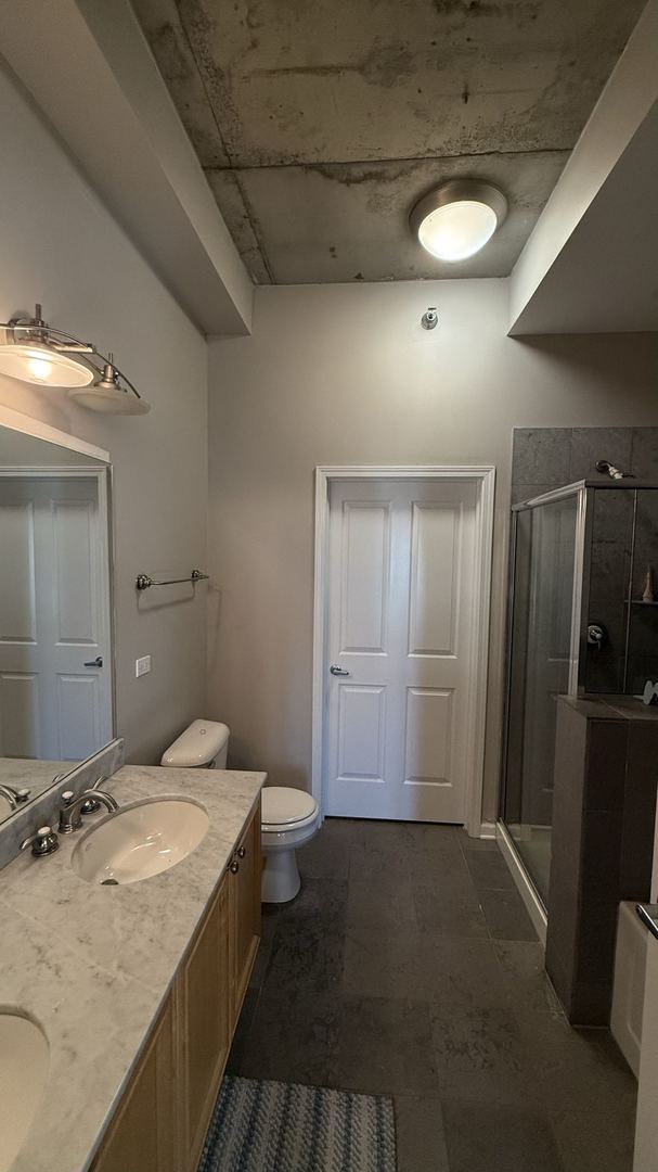 bathroom featuring vanity, toilet, and walk in shower