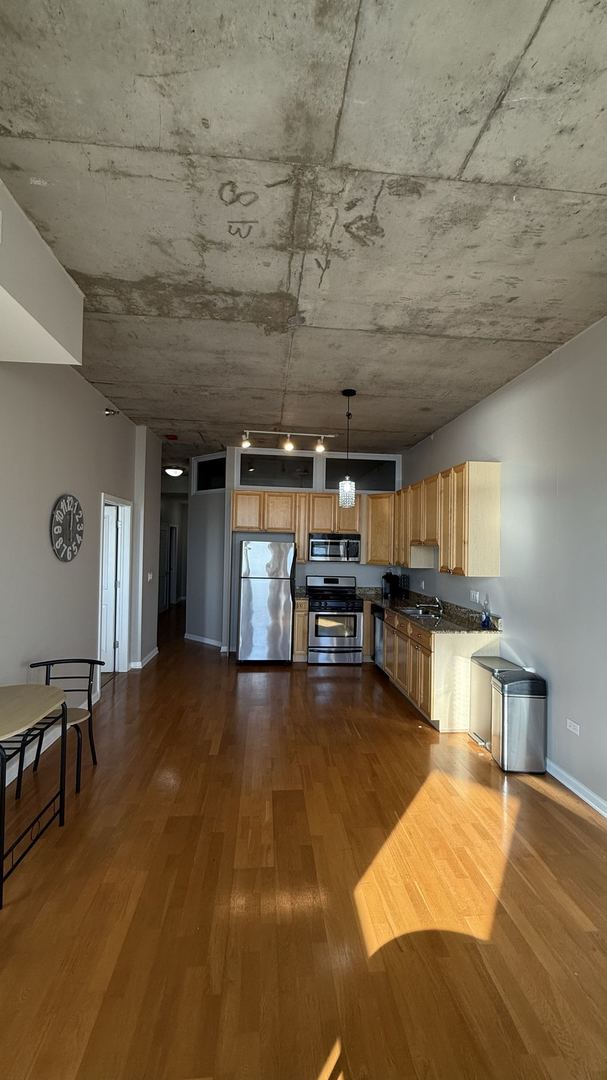 kitchen with sink, stainless steel appliances, wood-type flooring, and decorative light fixtures