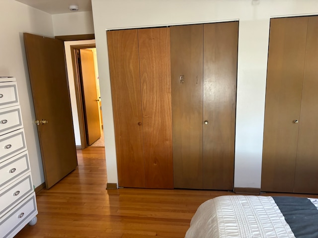 bedroom with light hardwood / wood-style flooring and two closets