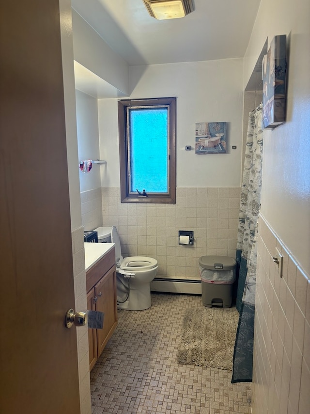 bathroom with a baseboard radiator, tile walls, toilet, vanity, and tile patterned floors