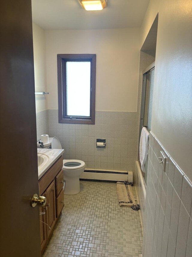 9270 N Courtland Dr, Niles, IL 60714 - full bath featuring tile walls, baseboard heating, wainscoting, vanity, and toilet