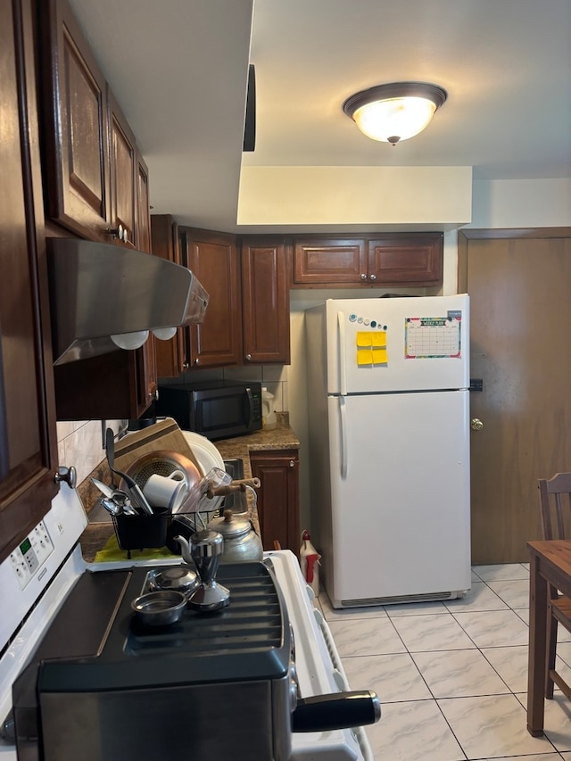 kitchen with exhaust hood, white fridge, and dark brown cabinets