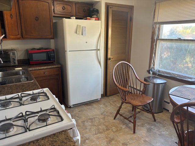 kitchen with sink, range hood, a baseboard radiator, and white appliances