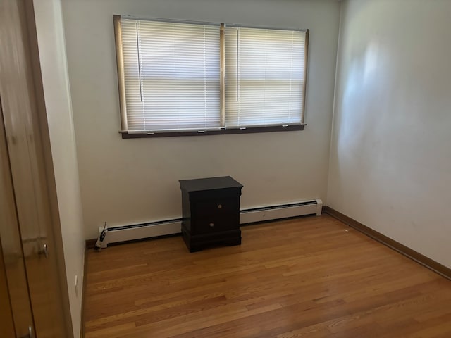 spare room with wood-type flooring and baseboard heating