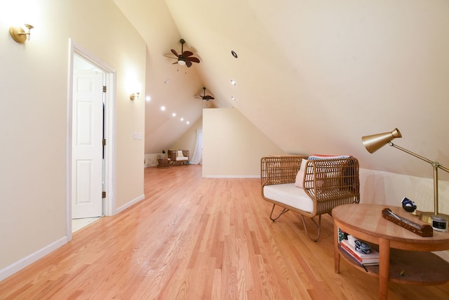 living area featuring ceiling fan, lofted ceiling, and light hardwood / wood-style flooring