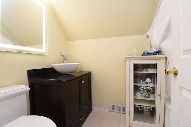 bathroom with vanity, lofted ceiling, and toilet