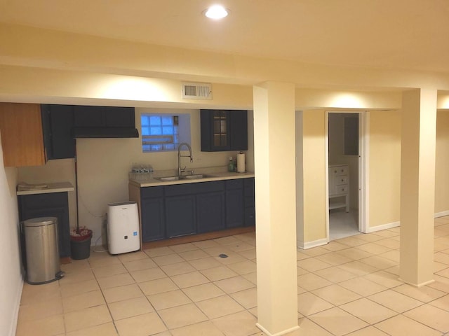 basement featuring light tile patterned flooring and sink