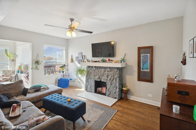 living room featuring a fireplace, a healthy amount of sunlight, dark wood-type flooring, and ceiling fan