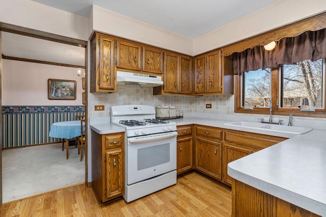 1617 Cimarron Dr, New Lenox, IL 60451 - kitchen featuring white gas stove, under cabinet range hood, brown cabinets, light countertops, and wainscoting