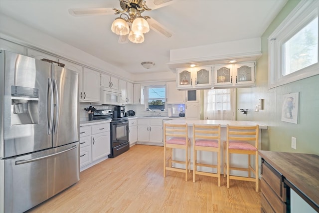 kitchen with a healthy amount of sunlight, stainless steel fridge with ice dispenser, white cabinets, and black / electric stove