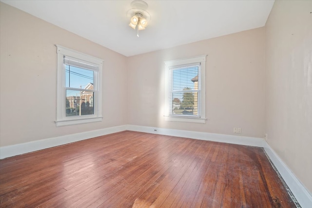 empty room with ceiling fan, a healthy amount of sunlight, and hardwood / wood-style floors