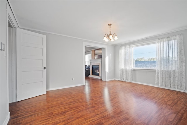 spare room featuring an inviting chandelier, ornamental molding, and dark hardwood / wood-style flooring