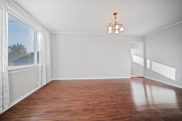 empty room with dark wood-type flooring, a notable chandelier, and ornamental molding