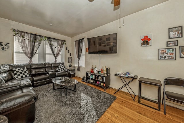 living room with hardwood / wood-style flooring, ceiling fan, and vaulted ceiling