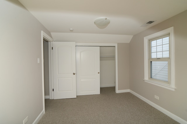 unfurnished bedroom featuring a closet, lofted ceiling, and carpet floors