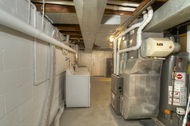 basement featuring water heater, washer and clothes dryer, and heating unit