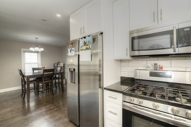 kitchen with dark wood-type flooring, appliances with stainless steel finishes, hanging light fixtures, and white cabinetry