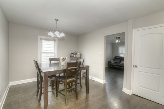 dining space with ceiling fan with notable chandelier and dark hardwood / wood-style flooring