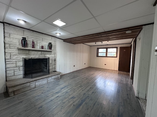 unfurnished living room with a paneled ceiling, wood walls, wood-type flooring, and a fireplace