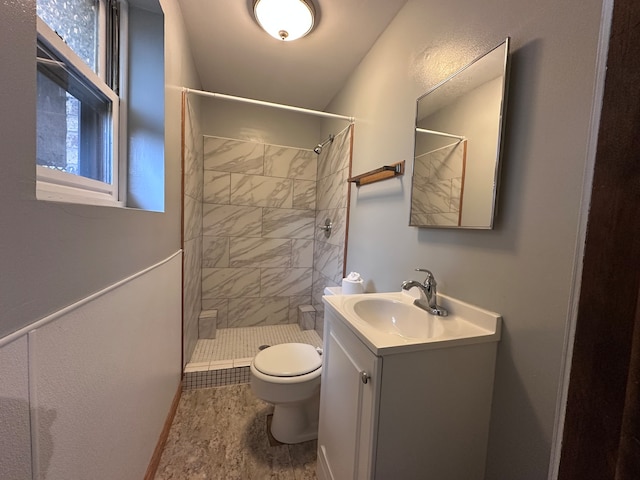 bathroom featuring vanity, a tile shower, and toilet