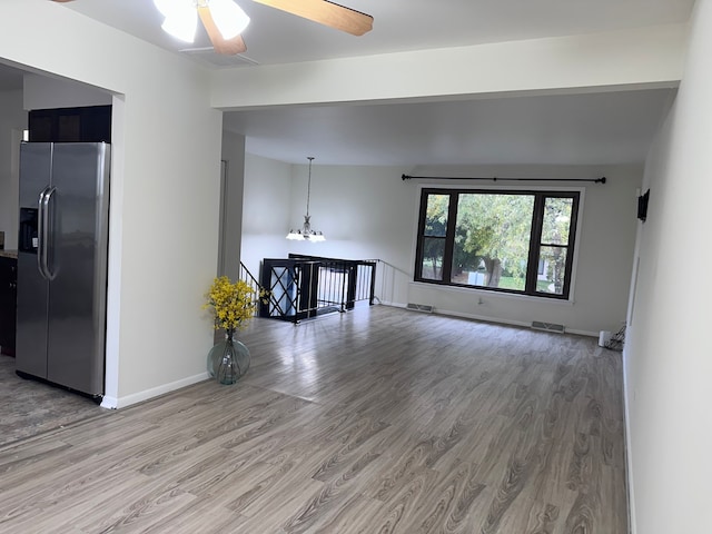 unfurnished living room with lofted ceiling, ceiling fan with notable chandelier, and hardwood / wood-style floors