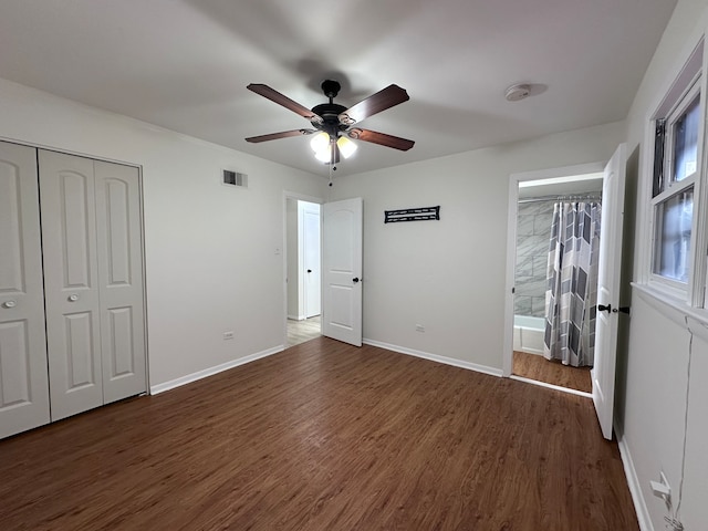 unfurnished bedroom featuring dark hardwood / wood-style flooring, a closet, ensuite bathroom, and ceiling fan