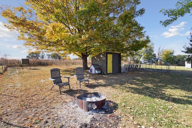 view of yard featuring a storage unit, a fire pit, and a rural view