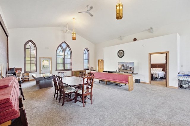 dining area with ceiling fan, light carpet, and high vaulted ceiling