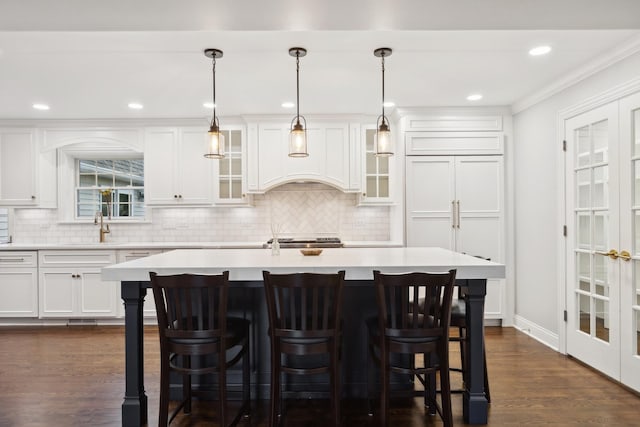 kitchen featuring white cabinetry, sink, dark hardwood / wood-style floors, decorative light fixtures, and a kitchen island with sink