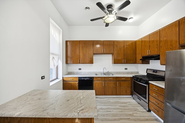 kitchen with appliances with stainless steel finishes, ceiling fan, sink, and light hardwood / wood-style floors