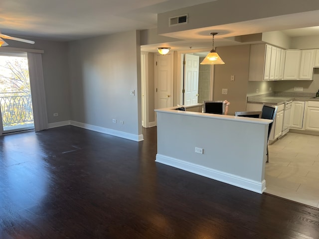 kitchen featuring white cabinetry, hardwood / wood-style flooring, hanging light fixtures, and ceiling fan