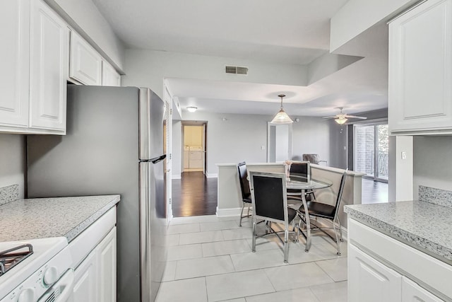 kitchen featuring pendant lighting, light wood-type flooring, white cabinetry, white stove, and ceiling fan