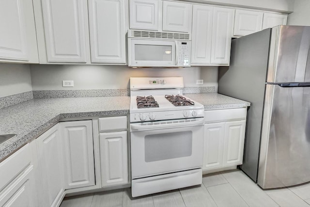 kitchen with white cabinetry, light tile patterned flooring, and white appliances