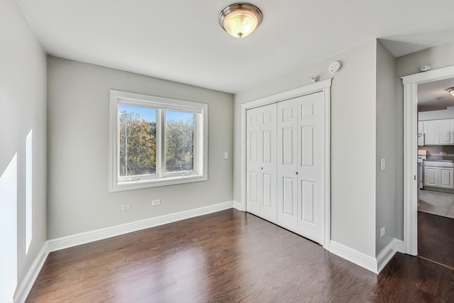 unfurnished bedroom featuring a closet and dark hardwood / wood-style flooring