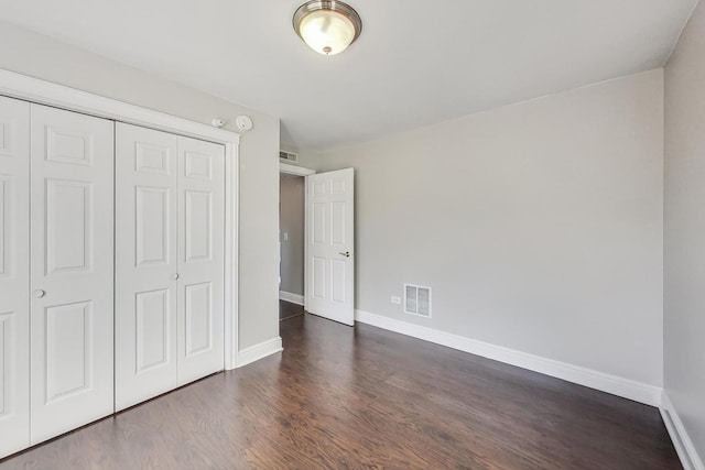 unfurnished bedroom featuring a closet and dark wood-type flooring