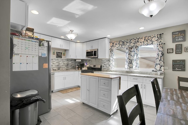 kitchen featuring appliances with stainless steel finishes, white cabinets, tasteful backsplash, and a center island