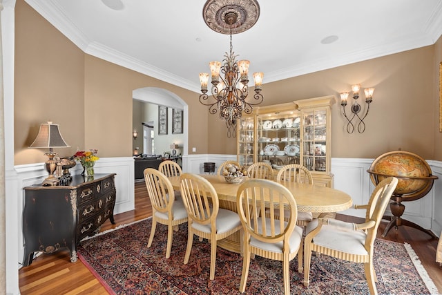 dining area with a notable chandelier, crown molding, and wood-type flooring