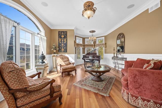 living room with a notable chandelier, ornamental molding, and light wood-type flooring