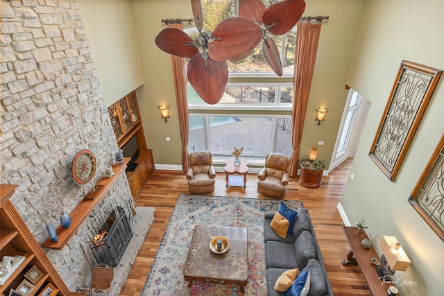 living room with a towering ceiling, plenty of natural light, a fireplace, and light wood-type flooring