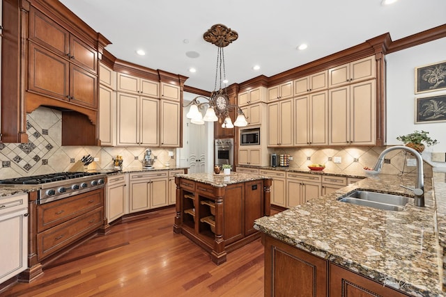 kitchen with sink, appliances with stainless steel finishes, hanging light fixtures, a center island, and cream cabinetry