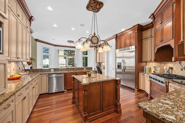 kitchen featuring sink, light stone counters, decorative light fixtures, kitchen peninsula, and stainless steel appliances