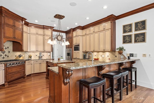 kitchen featuring appliances with stainless steel finishes, pendant lighting, light hardwood / wood-style floors, kitchen peninsula, and light stone countertops