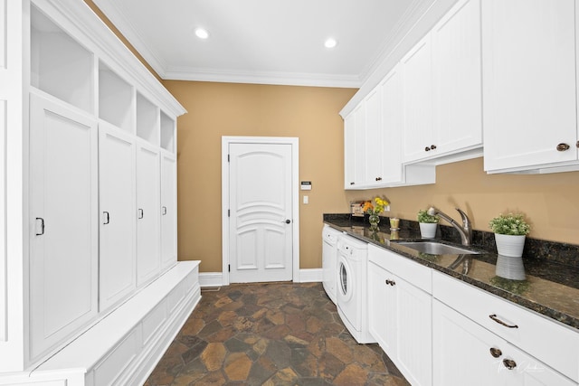 kitchen featuring sink, ornamental molding, dark stone counters, washer / clothes dryer, and white cabinets