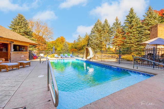 view of pool with a water slide and a patio area