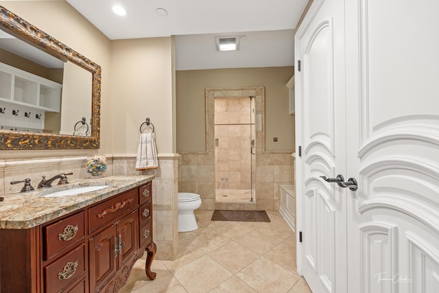 bathroom featuring a tile shower, tile walls, tile patterned flooring, vanity, and toilet