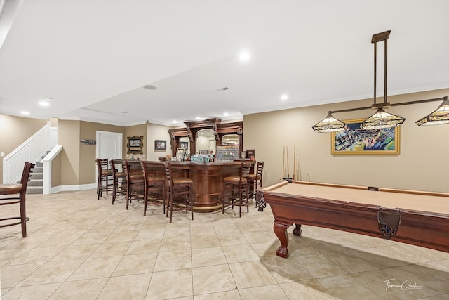 game room with light tile patterned flooring, ornamental molding, and bar area